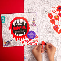Main d'enfant collant un sticker rouge sur le poster Vampire OMY