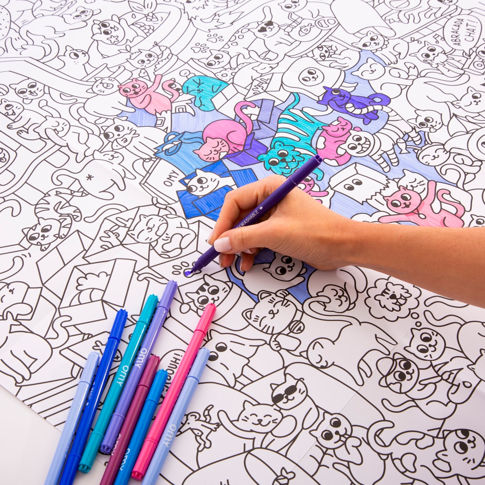 Main d'enfant coloriant le poster Kitty avec des feutres fluo sur fond illustré