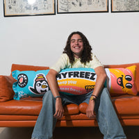 Smiling young man sitting on an orange sofa, hugging the OMY Freezy pouf shaped like a giant water ice