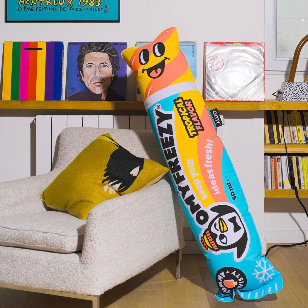OMY Freezy pouf shaped like a giant tropical-flavor water ice, placed against an armchair in a living room