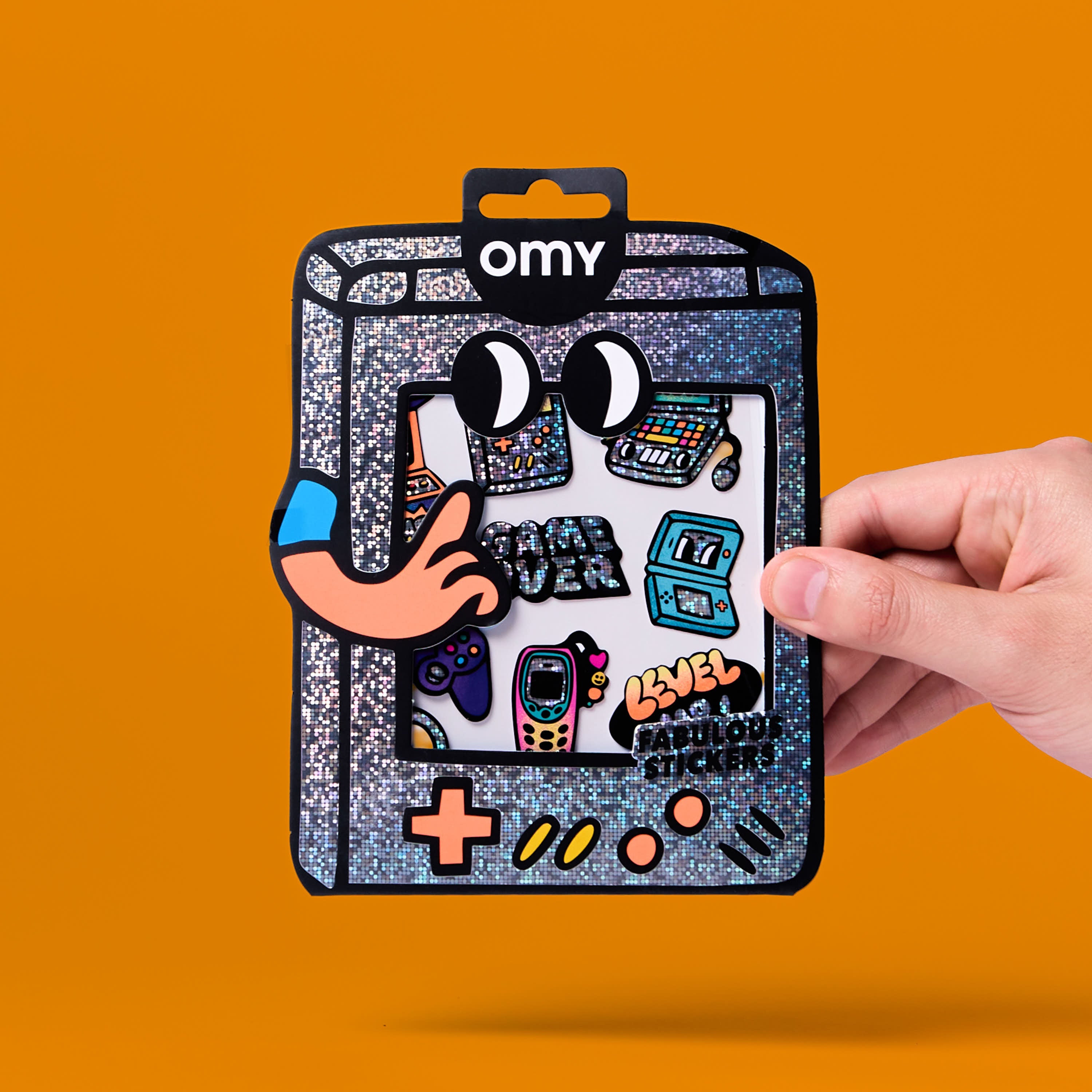 Packaging des stickers Game Boy OMY tenu en main, planche de stickers vinyle holographiques gaming