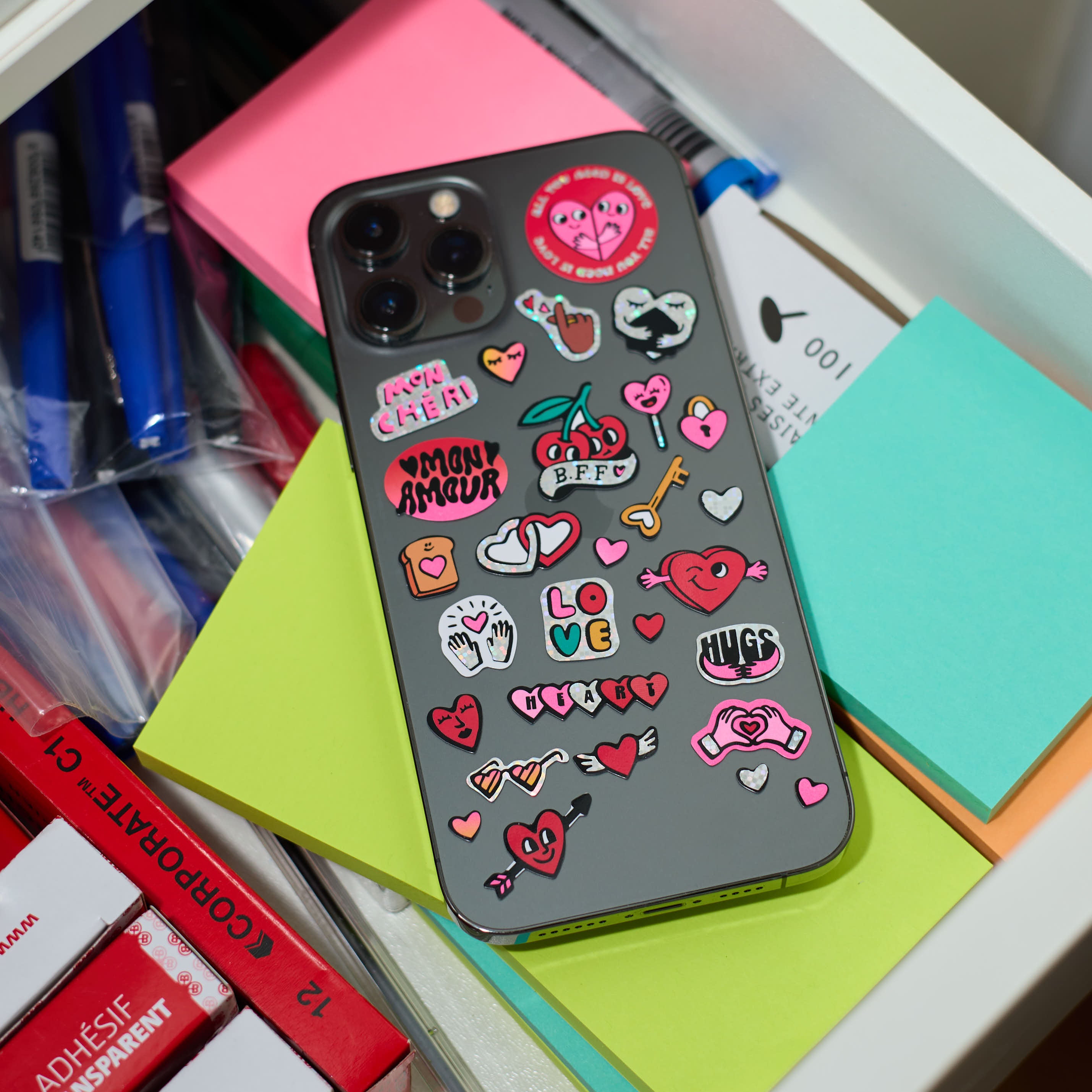 Stickers Iconic Love OMY collés sur un téléphone, cœurs et messages d’amour holographiques pour personnalisation d’objets