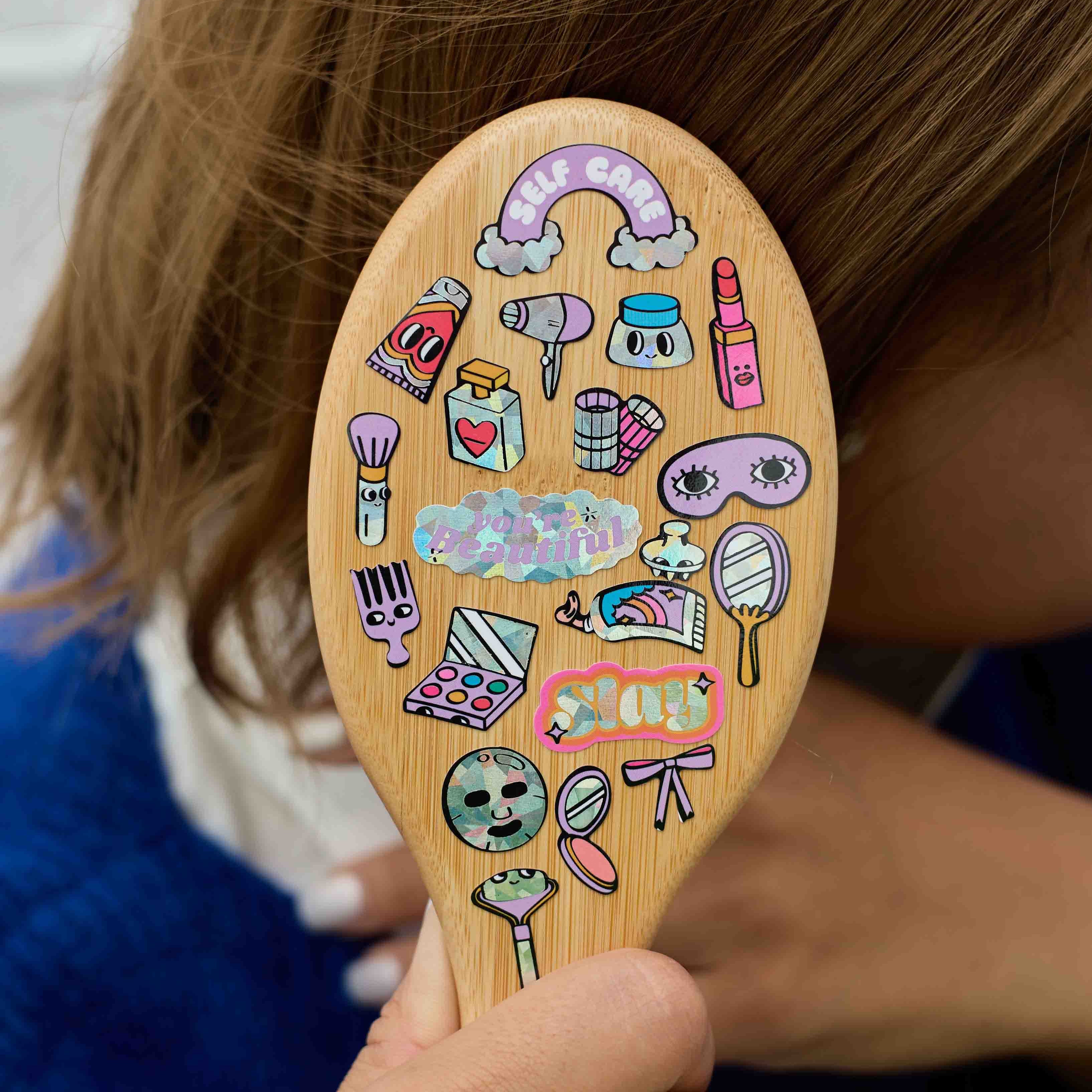 Holographic make-up stickers by OMY on a hairbrush, with lipsticks, mirrors and beauty accessories