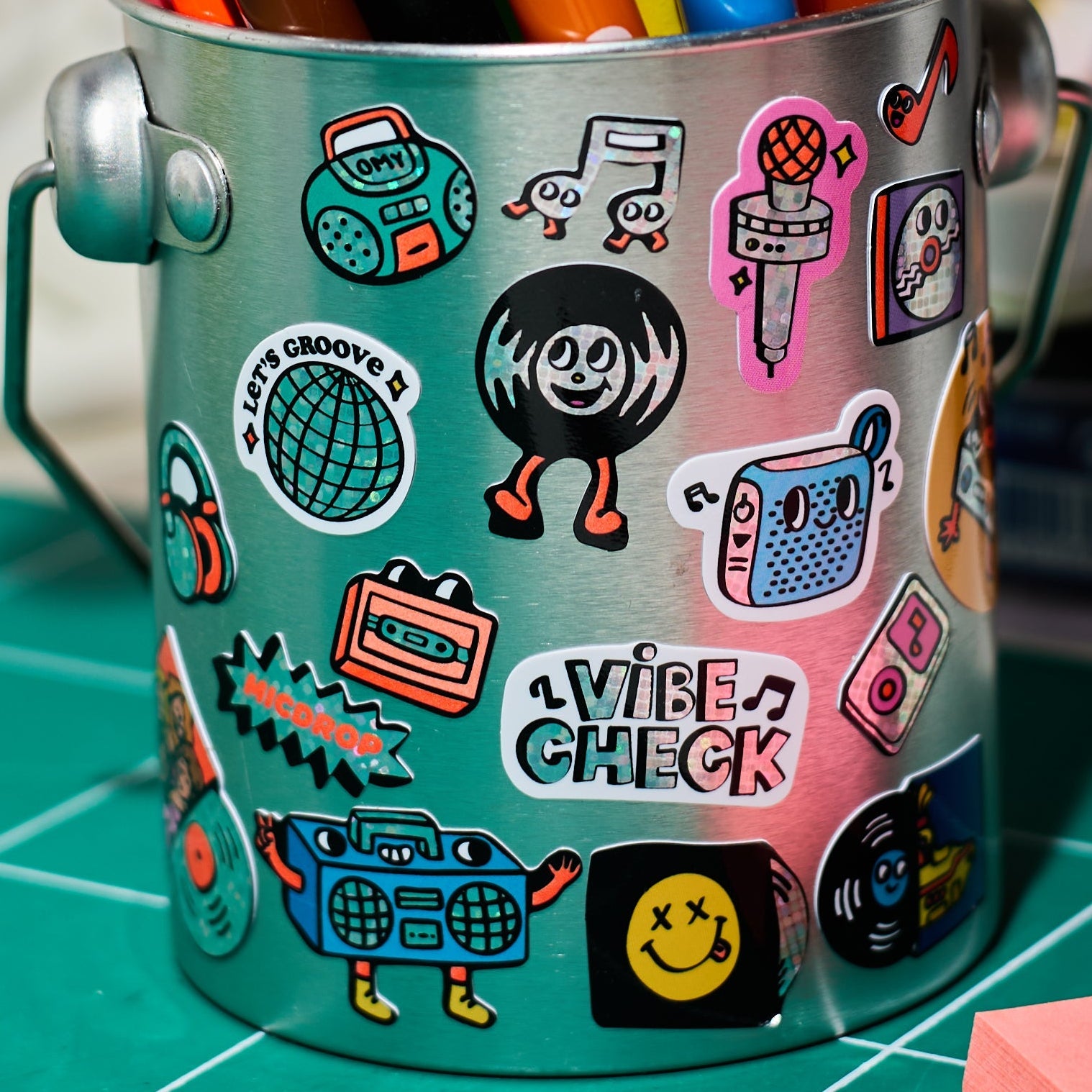 Holographic music stickers by Fabulous Stickers OMY stuck on a metal pencil pot, with vinyl records, microphones, radios and vinyl records