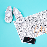 Kids' Superga x OMY velcro sneakers to color and matching coloring poster with pencils, on a turquoise background