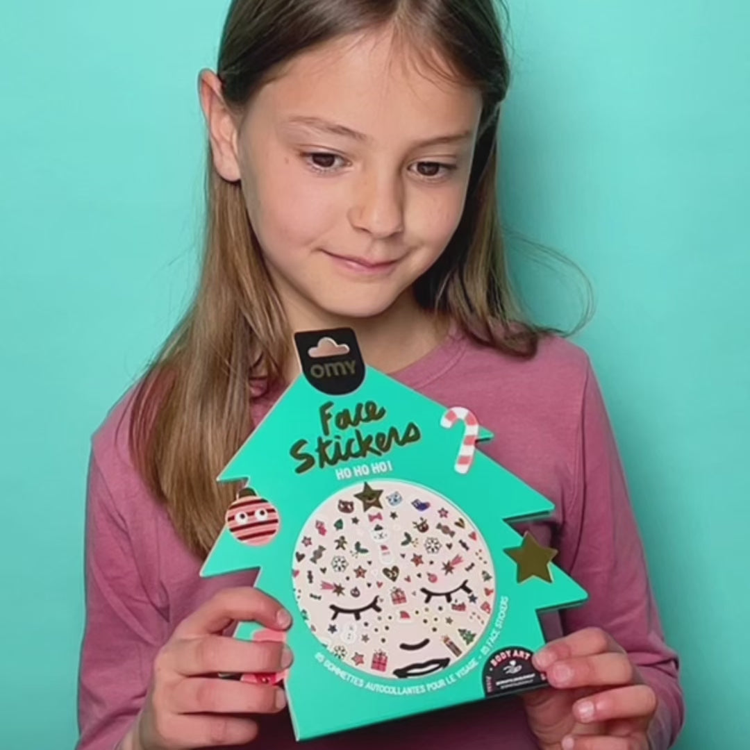 Vidéo d'une petite fille présentant la pochette Face Stickers Ho Ho Ho OMY en forme de sapin, gommettes de Noël pour le visage