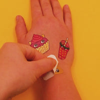 Vidéo d'application des tatouages éphémères Kawaii OMY sur une main : cupcake chat et gobelet de boisson