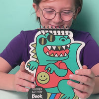 Vidéo d'une fille souriante présentant le Sticker Activity Book Dino OMY, carnet à stickers à spirale en forme de dinosaure turquoise